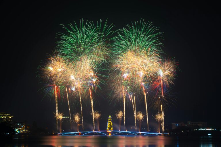 Colorful fireworks exploding over a lit bridge at night, showcasing a festive celebration.